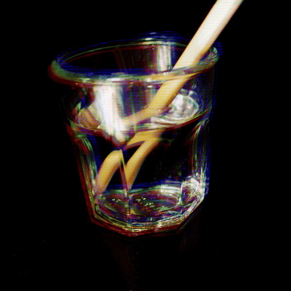 clear glass of water refracting a straw. rgb is out of alignment